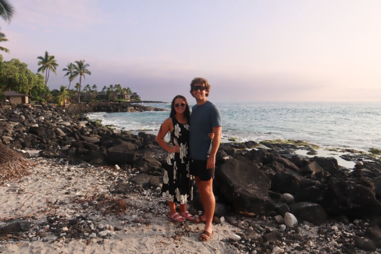 Brendon and Kaylee standing on a rocky Big Island shoreline at sunset