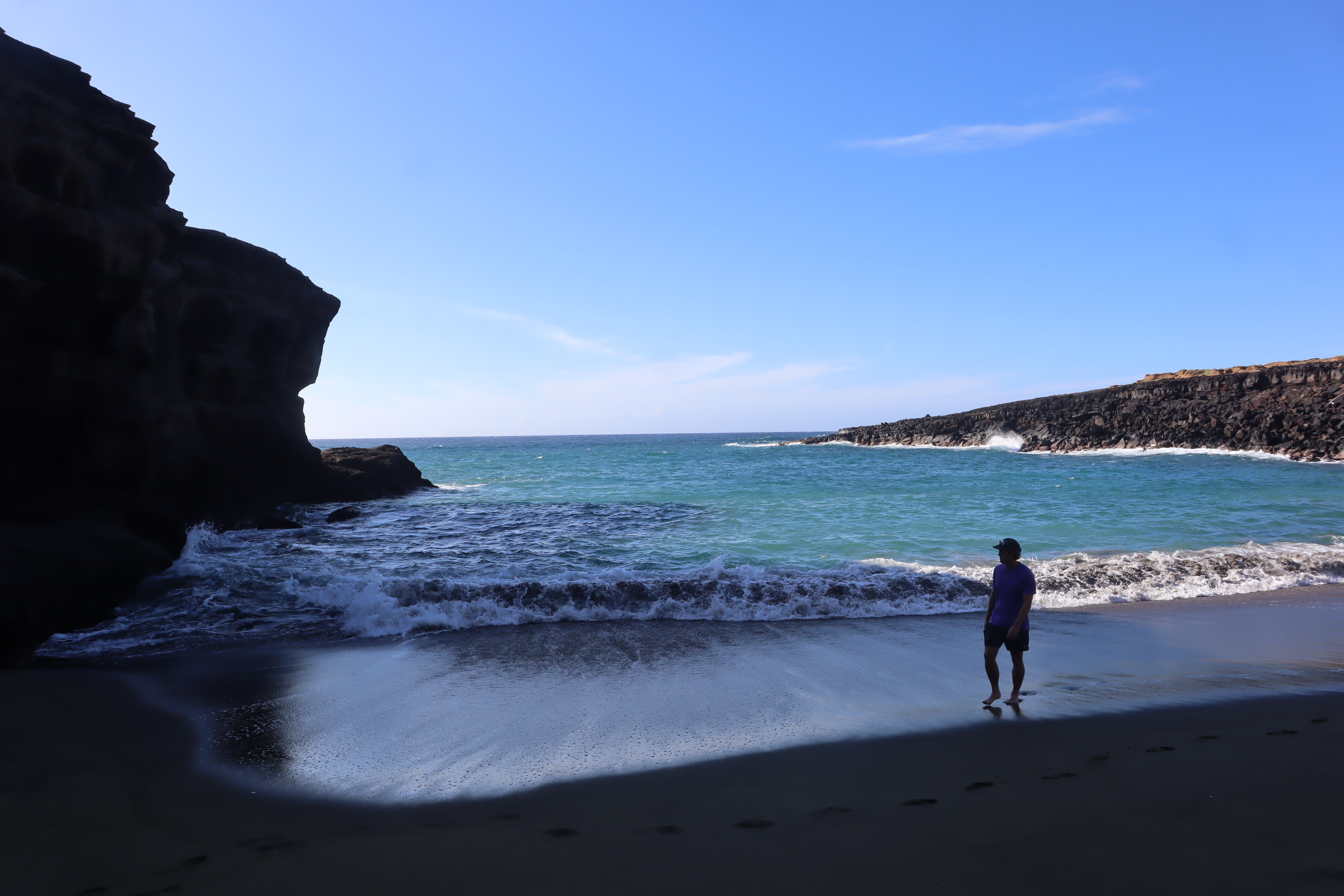 A person standing near waves inside a sheltered beach cove