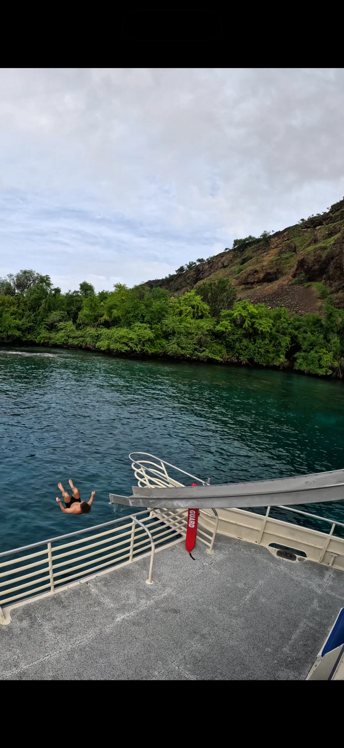 A boat slide extending toward the water beside a green coastline